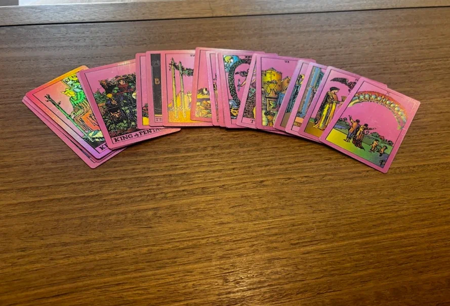 Holographic tarot deck fanned out on a wooden table
